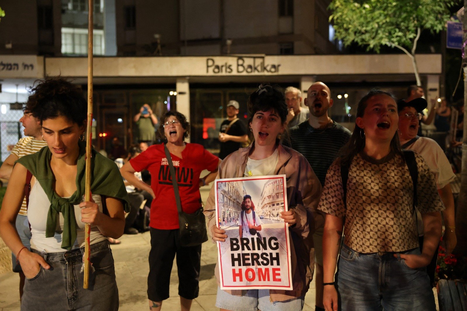 以色列人质的亲属和支持者周三晚在以色列总理官邸附近抗议，他们手举一张印有23岁以色列裔美国人质赫什图像的海报。（图取自法新社）